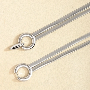 Detailed view of polished silver snake chain necklace and hoop earrings on beige background