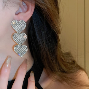 Detail of silver triple heart drop earrings featuring micro-pave crystal fringe