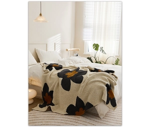 Detail of Nordic knitted floral blanket with large sunflower patterns on a bed