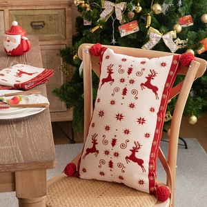 Close-up of a festive knit Christmas pillow with reindeer patterns and red tassels