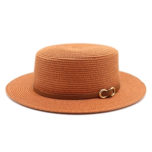 Détail d'un chapeau de paille avec bande en cuir marron et boucle dorée en fer à cheval