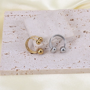 Minimalist 18K gold and silver stainless steel open sphere rings on a silk background