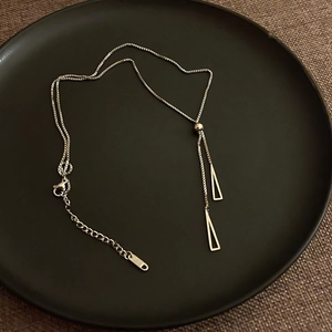 Detail of silver long necklace with adjustable bead and geometric triangle pendants