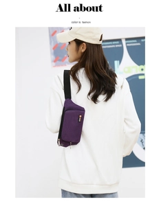 Detail of purple canvas fanny pack featuring black adjustable strap and metal zippers