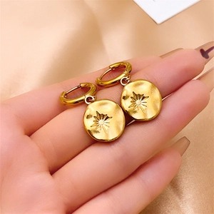 Boucles d'oreilles créoles dorées avec gravure d'étoile et texture martelée sur satin