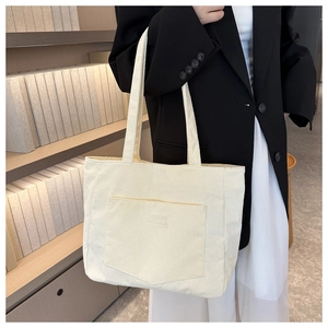 Detail of cream corduroy tote bag showing textured fabric and front patch pocket