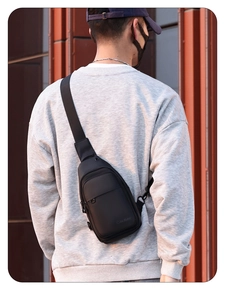 Men's black crossbody chest bag shown on model with street style background