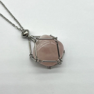 Detail of pink crystal stone in a silver metal mesh frame pendant on a steel chain