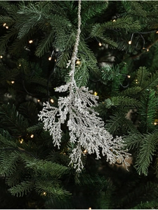 Sparkling silver cypress branch ornament hanging on a Christmas tree with festive lights