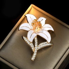 Macro shot of lily flower brooch with white enamel petals and gold crystal accents