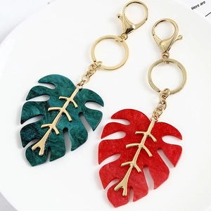 Macro detail of monstera leaf keychains with marble texture resin and golden plating