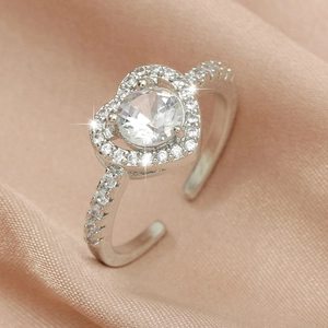 Macro shot of a sparkling heart ring with a large center stone on pink satin fabric