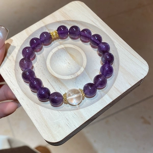 Macro shot of natural purple amethyst beaded bracelet with gold spacers on wooden tray
