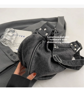 Detailed close-up of a black washed denim crescent bag with silver metallic hardware