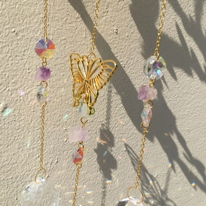 Detail of golden butterfly crystal suncatcher with purple beads and faceted glass ball