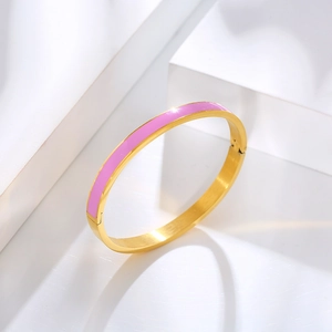 Detail of pink enamel inlay on a gold minimalist stainless steel bangle bracelet