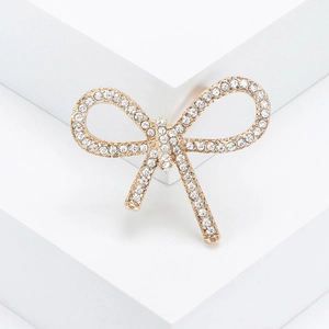 Elegant gold-tone bow brooch with sparkling rhinestones on a white pedestal display