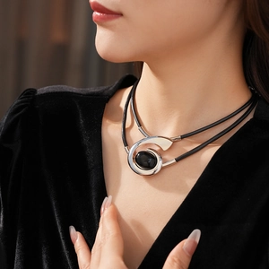 Close-up of vintage oval black gemstone pendant with layered cord on model's neck