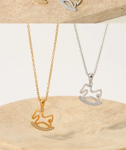 Detail of gold and silver rocking horse pendants with sparkling rhinestones and metal chain