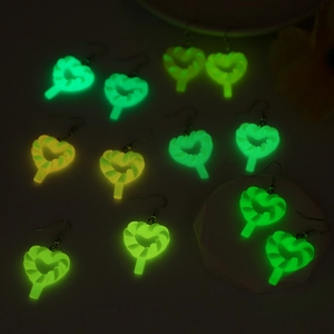 Boucles d'oreilles sucettes cœur lumineuses brillant en vert et orange sur fond noir