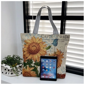 Detail of canvas tote bag with sunflower print, striped handles, and spacious interior
