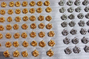 Detailed macro view of gold and silver rose earrings with layered petals in bulk display