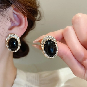 Detail view of vintage oval stud earrings with black center stone and shimmering diamonds