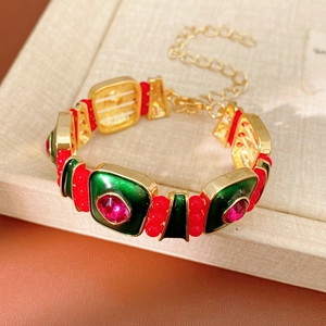 Detail of vintage gold bracelet with green enamel links and red gemstones on jewelry box