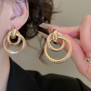 Détail de boucles d'oreilles doubles anneaux dorés avec surfaces lisse et texturée