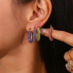 Close-up of model wearing gold earrings with multi-color zircon crystals and hoop design