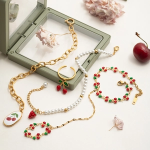 Detailed close-up of cherry jewelry set featuring red enamel pendants and gold chains