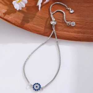 Adjustable silver box chain bracelet with sparkling blue evil eye charm in casual setting
