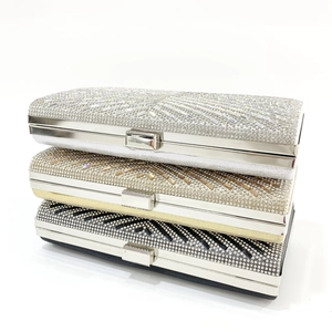 Close-up of three elegant clutch purses in silver, gold, and black with X-shaped stripe rhinestones