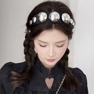 Close-up of a black fabric headband with polished silver spheres on a female model