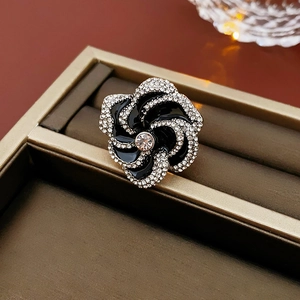 Macro shot of a floral brooch with black enamel petals and sparkling rhinestones