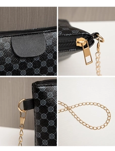 Detail of black crossbody bag with clover print, gold zippers, and metal chain strap