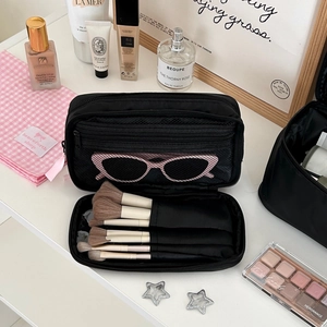 Detail view of black makeup bag with dedicated brush slots and a mesh pocket for storage