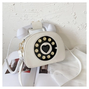 Close-up of white retro rotary phone crossbody bag with heart dial and handset handle