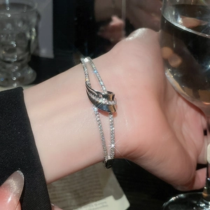 Détail macro d'un bracelet nœud argenté orné de zircons dans un cadre social chic