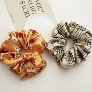 Detail of satin scrunchies featuring floral and houndstooth patterns on beige background