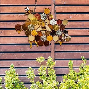 Detail of bee and honeycomb acrylic suncatcher hanging on a brown wooden fence