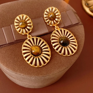 Macro shot of vintage gold sunburst earrings with tiger eye stone on a brown velvet box
