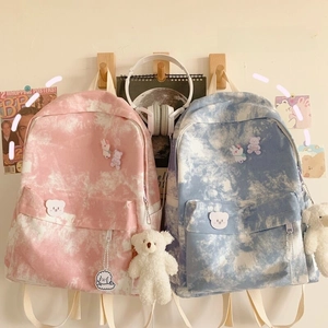 Detail of tie-dye canvas backpacks with cute plush bear charms and cartoon animal patches