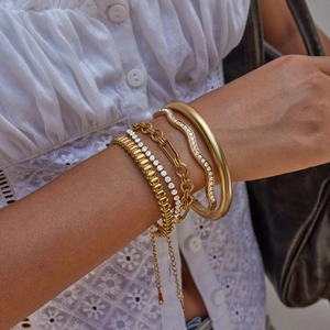 Gros plan de bracelets et chaînes superposés en acier inoxydable plaqué or 18 carats
