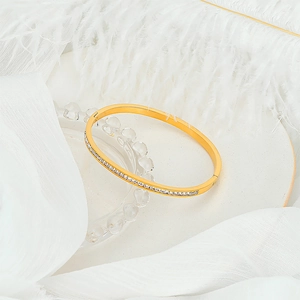Detail of rose gold titanium bracelet with half-circle white zircon inlay on white feather