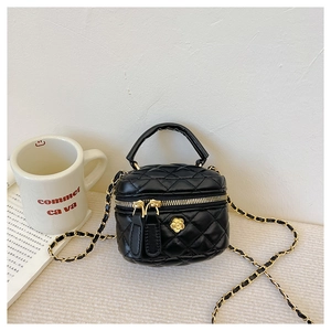 Close-up of black quilted mini bag with gold flower accent and chain strap