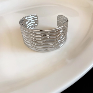 Detaillierte Nahaufnahme der eleganten Wellenstruktur auf silbernem Metallarmreif