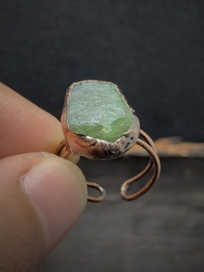 Macro detail of natural green raw stone set in a rustic copper adjustable open ring