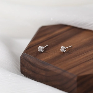 Minimalist S999 sterling silver rose flower stud earrings on a walnut wood base