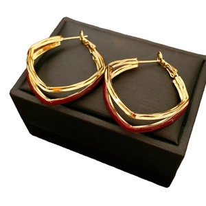 Gold geometric rhombus hoop earrings with red enamel on a brown jewelry box display